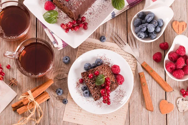 Chocolate sponge cake with fresh fruit on white dish.