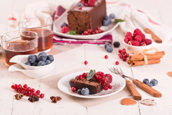 Chocolate sponge cake with fresh fruit on white dish.