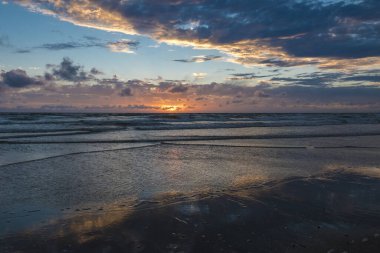 Günbatımında sakin bir sahil dramatik bir gökyüzü ve Danimarka 'daki Havneby' e doğru yol alan yansıtıcı su..