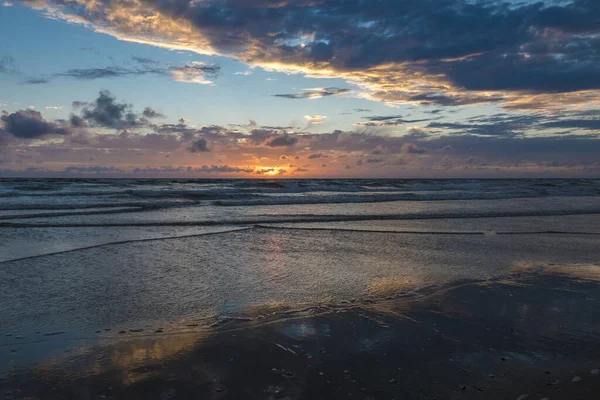 Günbatımında sakin bir sahil dramatik bir gökyüzü ve Danimarka 'daki Havneby' e doğru yol alan yansıtıcı su..