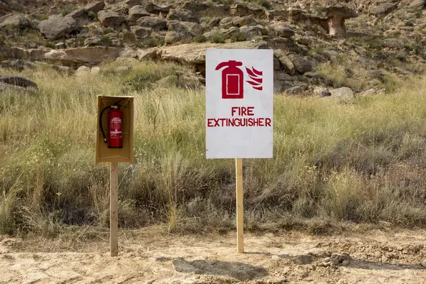 Red Fire sign and fire extinguisher with nature in the background