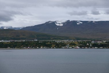 İzlanda 'da, bulutlu bir gökyüzünün altında karla kaplı dağlar yuva yapmış..