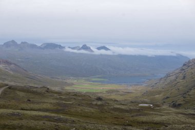 İzlanda 'da dağlar, bir göl ve bulutlu bir gökyüzü olan bir vadi..