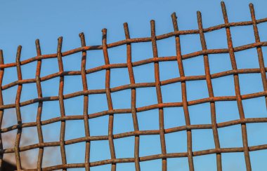 Old iron mesh fence against the sky