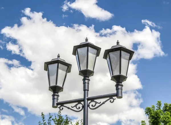 Street lamp in the park against the background of the sky with clouds