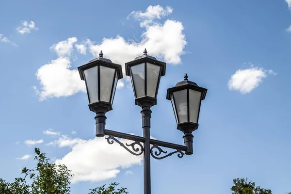 Street lamp in the park against the background of the sky with clouds