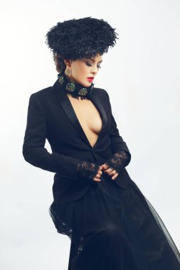 Siyah takım elbiseli, siyah tüllü etekli, siyah tüylü şapka takan güzel bir kadın.