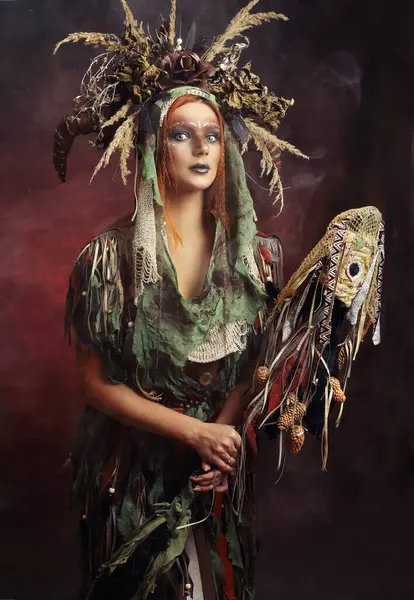 Wild fantasy shaman wizard warloc woman in boho dress and floral crown with horns holing magic stuff in her hand