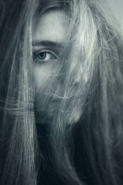 Saçı tarafından saklanmış bir kızın yüzü. Bir gözü sana bakıyor.