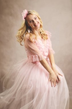 Çiçek aksanlı ve başlıklı pembe tüllü bir kadının neşeli stüdyo portresi. Bu görüntü moda, güzellik ya da özel durum temalı içerik için mükemmeldir, zarafet ve neşe vurgular..