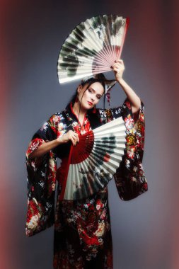 40 'larında güzel siyah saçlı bir kadın Japon kıyafetleri giyiyor. Kırmızı kimono.