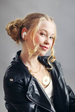 Müzik dinleyen 10 yaşındaki sarışının modern portresi. Mini kulaklıklar gençliği moda ve müzik tarzıyla ön plana çıkarıyor