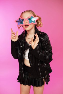 K Pop 'ta 10 yaşında şık bir kız. Pembe güneş gözlüğü takıyor ve parlak pembe bir arka planda izole edilmiş.