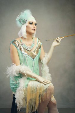 Flapper gibi giyinmiş güzel bir kadının görüntüsü. Kadınlar stil sahibi, eğlenceli bir duruşu ve harika bir ifadesi var.
