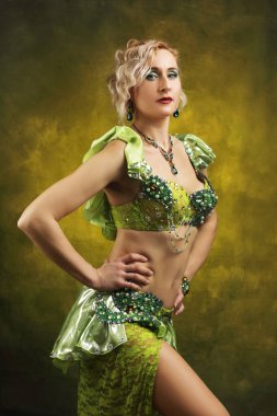 Karmaşık detaylı zümrüt yeşili kostümlü kendinden emin bir dansçının çarpıcı portresi. Kültür ve performans temaları için mükemmel