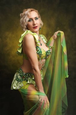 Karmaşık detaylı zümrüt yeşili kostümlü kendinden emin bir dansçının çarpıcı portresi. Kültür ve performans temaları için mükemmel