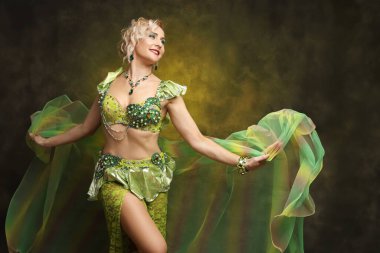 Karmaşık detaylı zümrüt yeşili kostümlü kendinden emin bir dansçının çarpıcı portresi. Kültür ve performans temaları için mükemmel