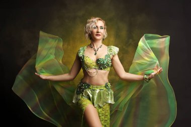 Karmaşık detaylı zümrüt yeşili kostümlü kendinden emin bir dansçının çarpıcı portresi. Kültür ve performans temaları için mükemmel