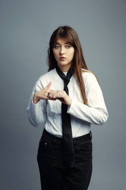 Gömlekli ve kravatlı genç bir kadın bir şeyi açıklarken düşünceli ya da gergin görünür. İş sunumları, röportajlar, dava oluşturma veya sosyal kaygı konsepti.