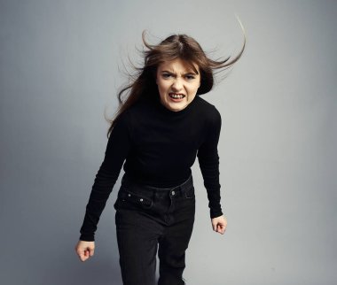 Öfkeli genç bir kadın, saçları uçuyor, homurdanıyor, yumruklarını sıkıyor, dişlerini gösteriyordu. Gri bir stüdyo geçmişine karşı siyah giyinmişti. Dinamik ve son derece agresif..