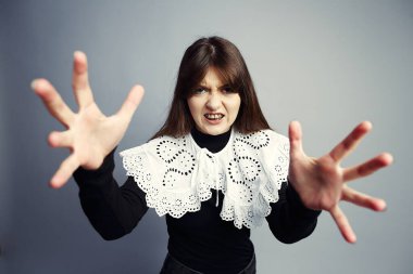 Hırıltılı ve keskin gözleri olan vahşi genç bir kadın agresif bir şekilde uzanıyor. Beyaz dantelli bir yaka ile siyah giyinmiş, düz gri bir stüdyo arka grubuna karşı