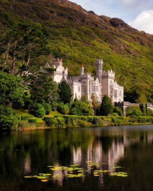 Kylemore Manastırı, Connemara Dağları 'ndaki yeşilliklerin arasında gölde yansıyor.