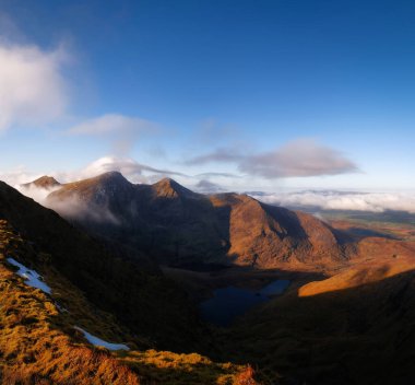 Carrauntoohil, Hag 's Glen Vadisi ve etrafındaki dağlar günbatımı tonlarında.