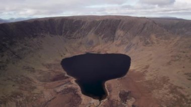 Sahne 4K hava görüntüleri, muhteşem dağ arazisi Connemara, Galway, İrlanda 'daki pitoresk dağ gölünün üzerinde uçtuğunu gösteriyor.