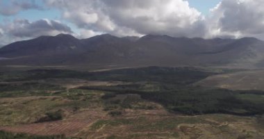 Gün batımında manzaralı dağların üzerinde ve dağların üzerinde uçtuğunu gösteren nefes kesici 4K hava görüntüsü, Connemara, Galway, İrlanda