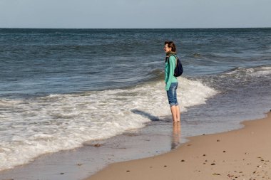 Gün batımından önce küçük deniz kabukları ve çakıl taşları olan kumsal.