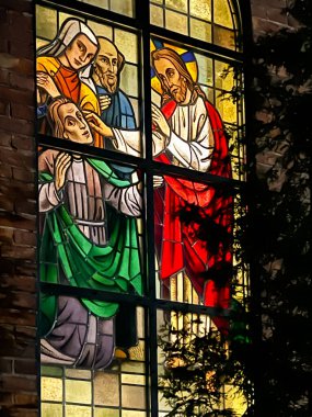 Kalety Miotek, Poland, January 1, 2023: Stained glass windows in the church of St. Francis, seen from the outside in the evening. Healing the blind, clipart