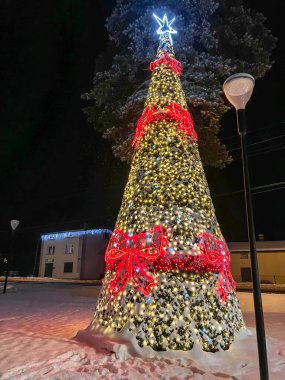 Illuminated and decorated Christmas tree, covered with snow in a small town in Poland.