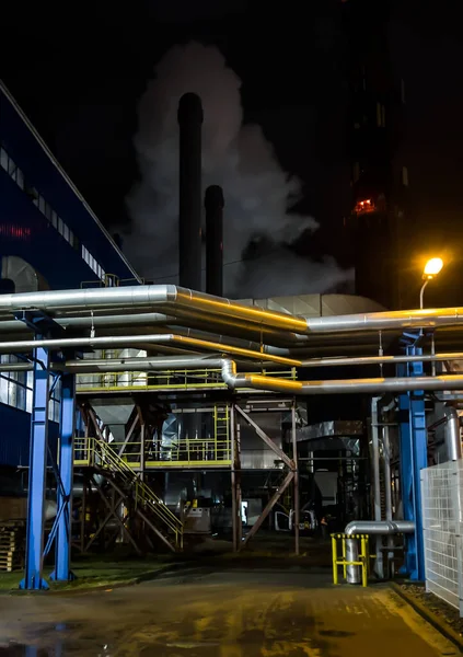 Chimney discharging fumes from a natural gas-fired boiler. Visible large amount of condensed water coming out of the chimney. Chimney emission measurement. Work at night.