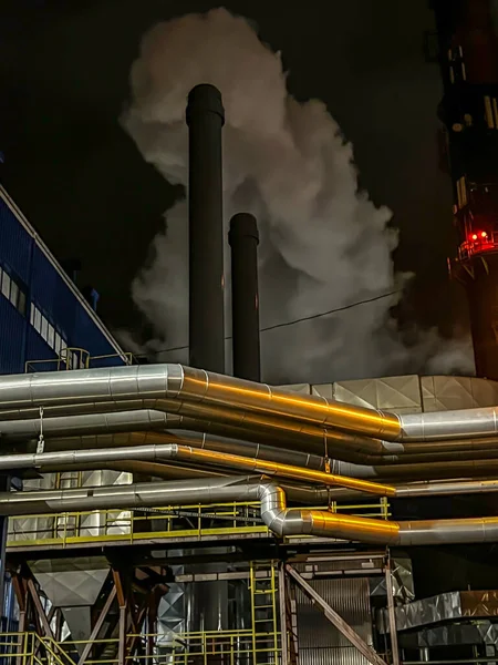 Chimney discharging fumes from a natural gas-fired boiler. Visible large amount of condensed water coming out of the chimney. Chimney emission measurement. Work at night.