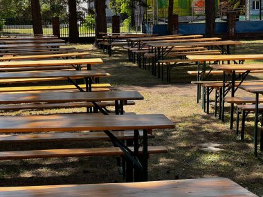 Masalar ve banklar ağaçların altındaki bahçede toplanmadan önce hazırlandı.