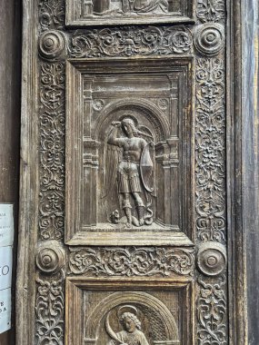 Napoli, İtalya - 28 Eylül 2023: eski ahşap bir kapının parçası. Napoli, İtalya 'daki St. Angelo a Nilo kilisesi için bas-yardım ile süslenmiş..