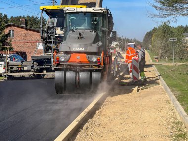Kalety, Polonya, 12 Nisan 2024: Yeni bir sokak yüzeyi inşaatı. Uzman bir makineyle asfalt tabakası sermek.
