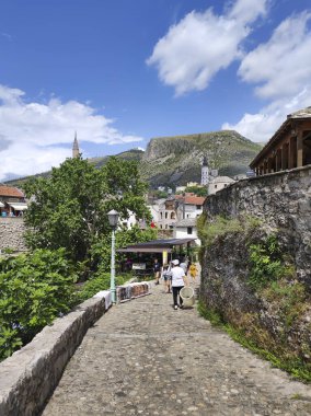 MOSTAR, BOSNIA VE HERZEGOVINA, 11 Haziran 2024: Eski binalar, restoranları ve kafeleri olan dar sokaklar ve Bosna-Hersek 'in Mostar kentinde turistleri bekleyen hediyelik eşya dükkanları.