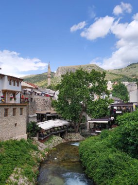 MOSTAR, BOSNIA VE HERZEGOVINA, 11 Haziran 2024: Bosna Hersek 'in Mostar kentinde turistleri bekleyen restoranları ve kafeleri olan eski binalar.