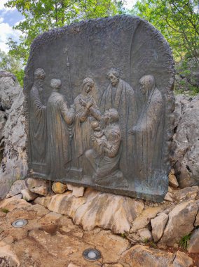 Podbrdo, Bosna, 10 Haziran 2024: Bosna 'nın Medjugorje köyüne bakan Hayalet Tepesi, Podbrdo Dağı' ndaki tespihin neşeli gizemlerini temsil eden yardım. İsa 'nın sunumu tapınakta.