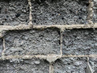 Arkaplan olarak harap olmuş beton ve kömür bloklarından yapılmış bir duvar parçası.