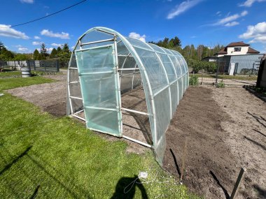 Baharda çerçeveye folyo koymak, bir sebze bahçesinde folyo çadırı kurmak..