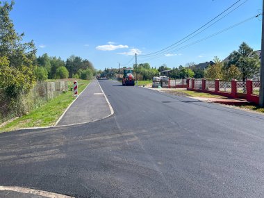 Son asfalt tabakasını modern yol ve kaldırıma seriyorum. Asfalt ve yol silindirleri döşeyen bir makinenin işletimi.