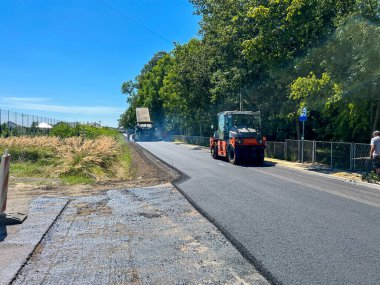 Renovation of a village road, making a layer of asphalt. clipart