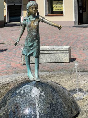 Lubliniec, Poland, August 13, 2024: A fountain on the market square in Lubliniec with a figure of St. Teresa Benedicta of the Cross as a child, because she used to visit her family there as a child. clipart