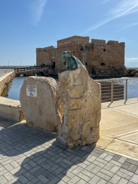 Paphos, Cyprus, October 13, 2024: A statue of a woman lying on a stone in the port of Paphos, Cyprus, in front of the castle. clipart