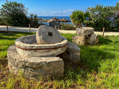 A millstone formerly used for squeezing olive oil and now used as decoration on the seaside promenade in Kissonerga, Cyprus. clipart