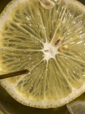 Bir bardak çayın içinde yüzen dilimlenmiş limon diliminin yakın çekimi..