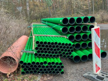 Kanalizasyon sahasında depolanmış arka plan olarak yan yana dizilmiş çubuklardaki yeşil kanalizasyon boruları.