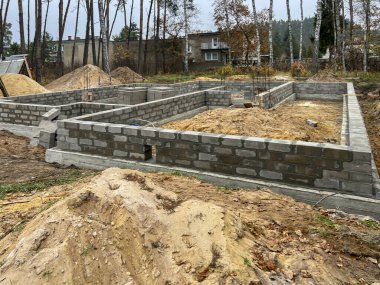 Çelik çubuklarla güçlendirilmiş beton zemindeki dört katmanlı beton bloklardan oluşan tek bir aile evinin temellerinin inşası.